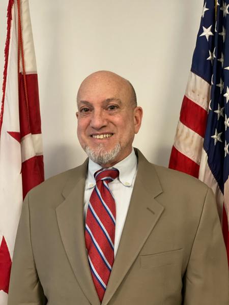 Ed Grandis Headshot with DC and US flags in background.
